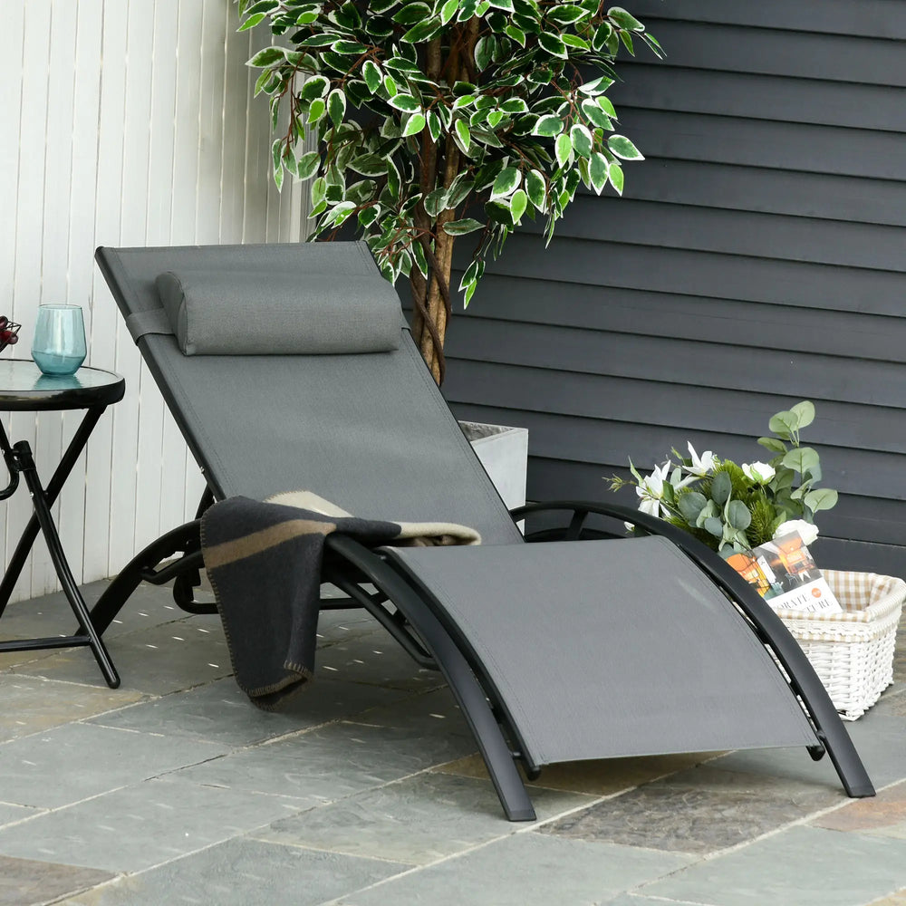 Chaise longue extérieure en résine tressée avec coussin gris sur terrasse ensoleillée