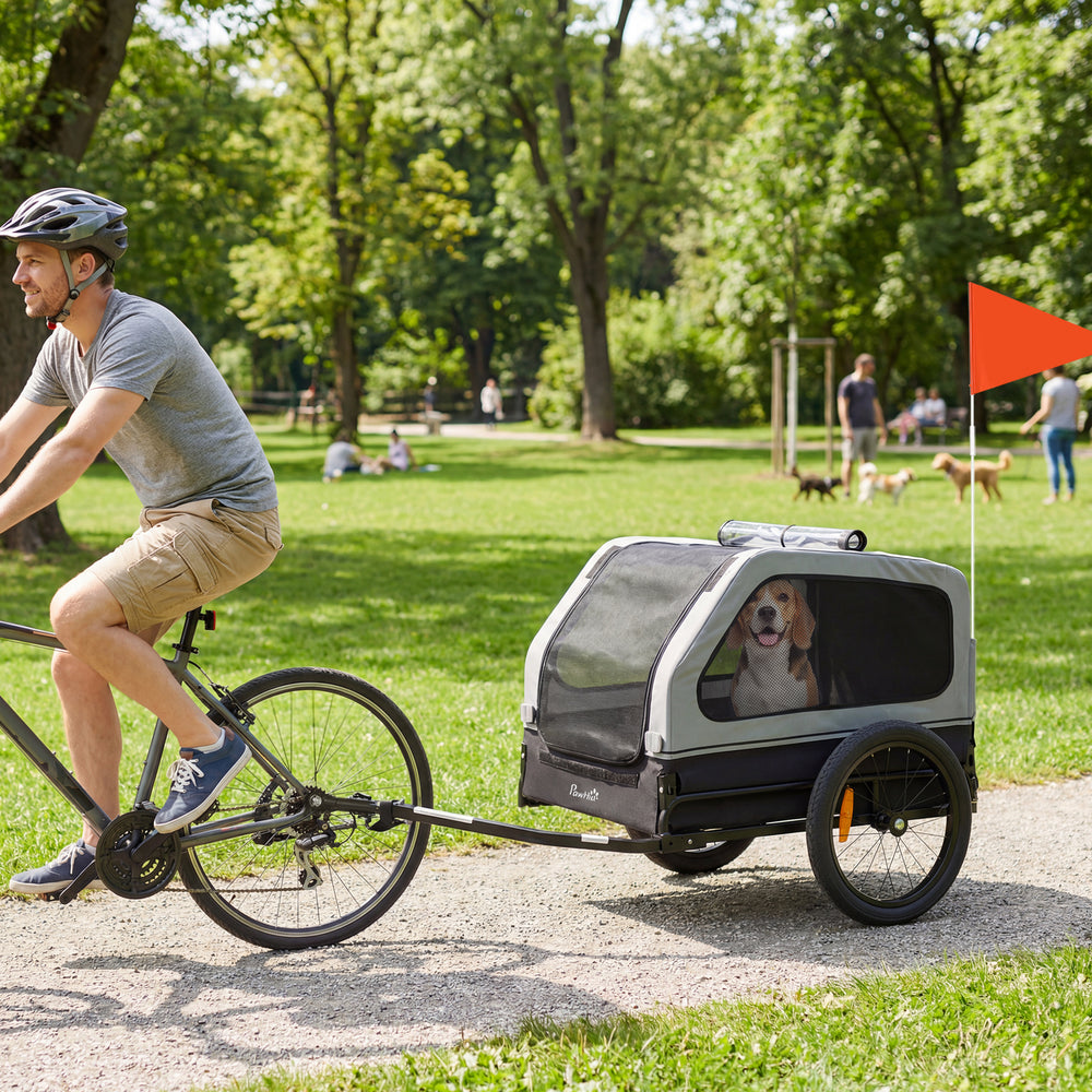Remorque vélo pour chien, adaptée aux chiens de petite et moyenne taille jusqu'à 20 kg, avec attelage universel et hayon à rampe rabattable, couleur grise.